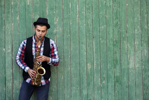 El músico toca el saxofón sobre fondo de madera verde —  Fotos de Stock