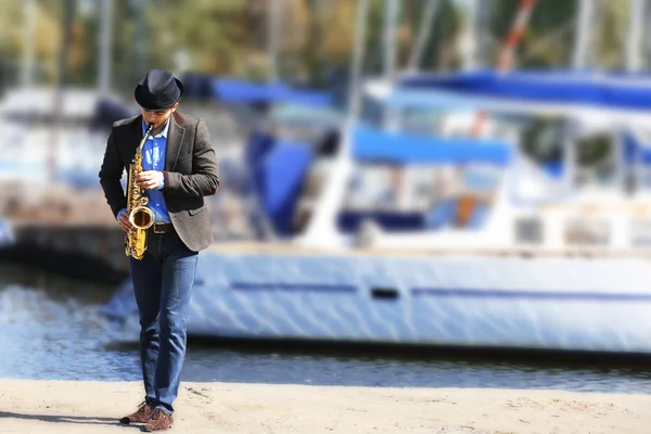 Un bell'uomo suona il sax davanti allo yacht — Foto Stock