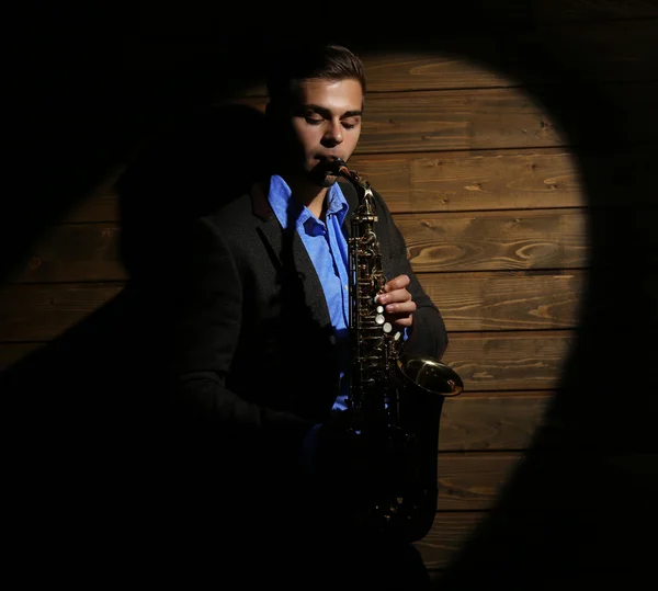 Elegante saxofonista toca jazz em fundo de madeira — Fotografia de Stock