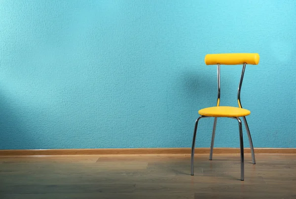 Cadeira amarela na parede azul — Fotografia de Stock