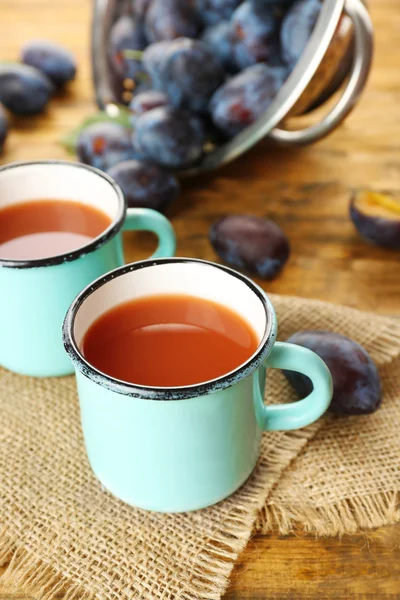Plum Juice in mugs with fresh fruits — Stock Photo, Image