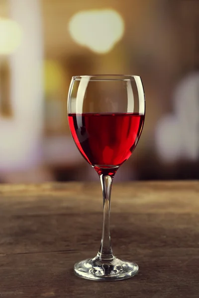 Ποτήρι κόκκινου κρασιού τύπου στο ξύλινο τραπέζι αόριστες φόντο — Φωτογραφία Αρχείου