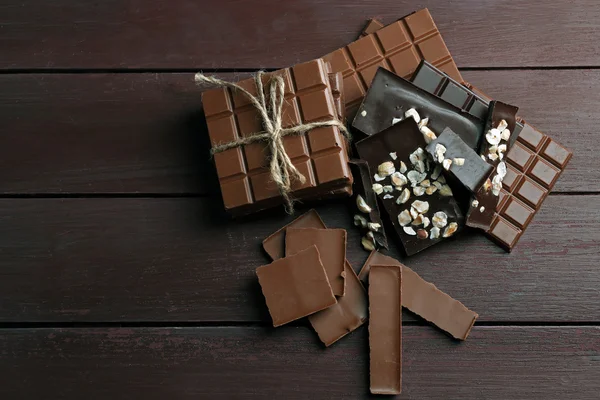 Różne kawałki czekolady na drewniane tła — Zdjęcie stockowe