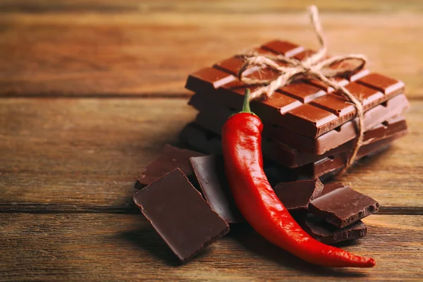 Zwarte chocolade stukken met peper op houten achtergrond — Stockfoto