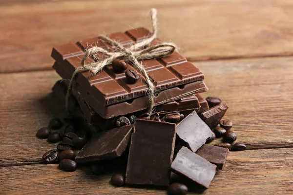 Melk chocolade stukken en koffie korrels op houten achtergrond — Stockfoto