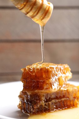 Ahşap arka plan üzerinde plaka üzerinde peteğin damlayan bal