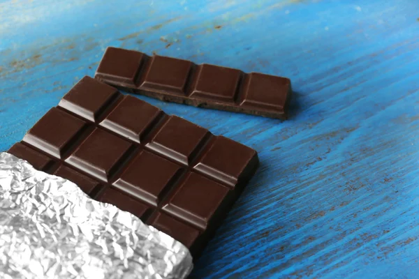 Tmavé čokolády v alobalu na šedém pozadí — Stock fotografie