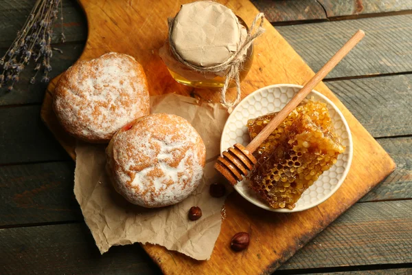 Pentes de mel na placa, pães quentes no fundo de madeira — Fotografia de Stock