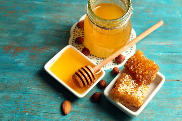 Favo, pentola di vetro con miele e noci su sfondo di legno a colori — Foto Stock