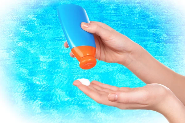 Bottle of suntan cream in hands — Stock Photo, Image