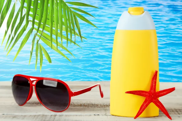 Bottle of suntan cream with sunglasses — Stock Photo, Image