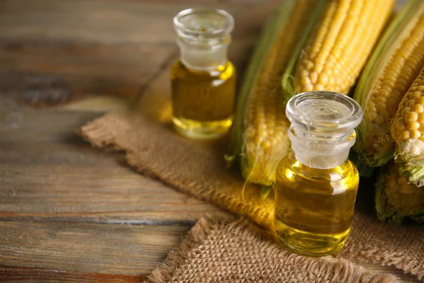 Fresh corn with bottles of oil — Stock Photo, Image