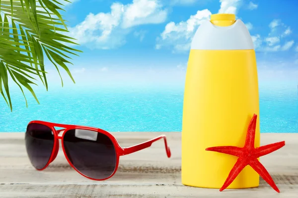 Botella de crema bronceadora con gafas de sol —  Fotos de Stock