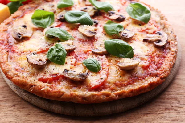 Gustosa pizza con verdure e basilico in tavola da vicino — Foto Stock