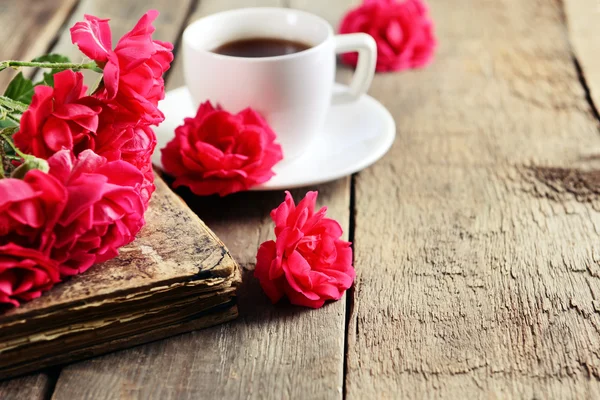 Vecchio libro con belle rose e una tazza di caffè sul tavolo di legno da vicino — Foto Stock