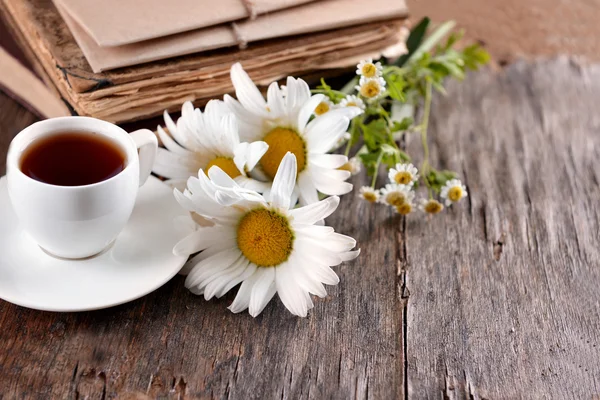 Libros antiguos con hermosas flores y taza de té en la mesa de madera de cerca —  Fotos de Stock