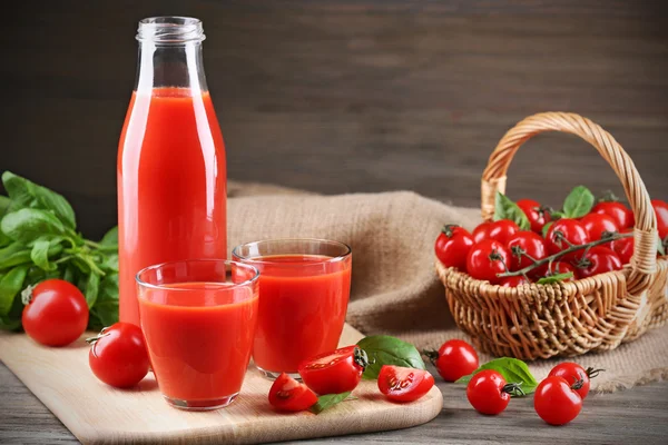 Bouteille pleine et verres de jus de tomate avec légumes sur table en bois fermer — Photo