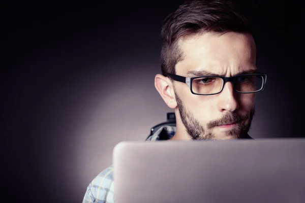 Jovem bonito com laptop no fundo cinza — Fotografia de Stock