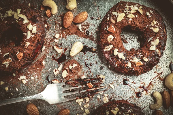 Donat lezat dengan lapisan coklat dan kacang-kacangan di atas meja. — Stok Foto