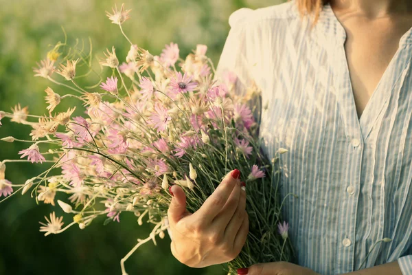 Mãos femininas com buquê de flores silvestres sobre palhetas fundo — Fotografia de Stock