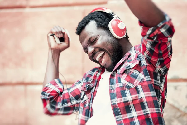 Hombre afroamericano escuchando música con auriculares al aire libre —  Fotos de Stock