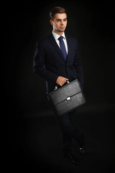 Елегантний чоловік у костюмі з портфелем на темному тлі — стокове фото