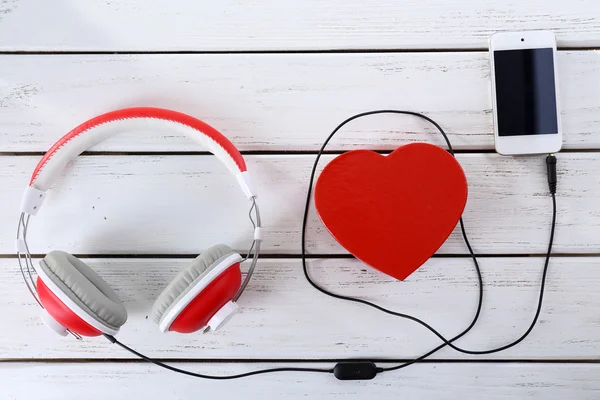 Headphones with heart and phone on wooden background — Stock Photo, Image