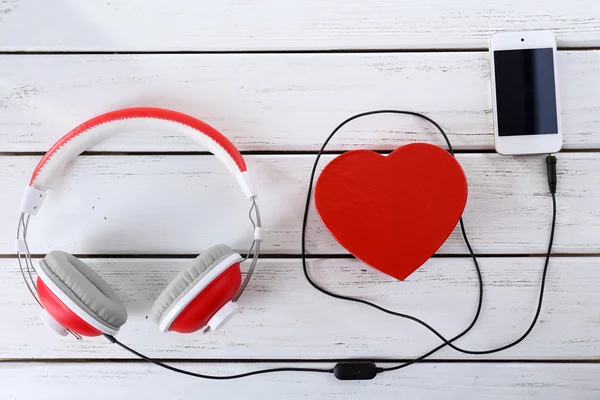 Cuffie con cuore e telefono su sfondo in legno — Foto Stock