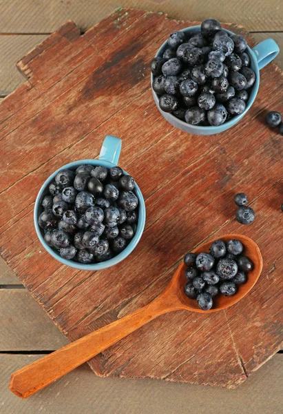 Bleuets frais dans des tasses et cuillère sur table en bois fermer — Photo