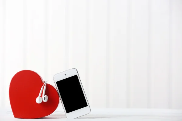 Fones de ouvido com coração e telefone no fundo branco — Fotografia de Stock