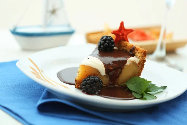 Leckerer Kuchen unter Schokoladenglasur mit Brombeere auf blauem Serviette — Stockfoto