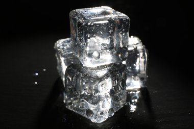 Buz küpleri koyu sıvı arka plan üzerinde parlayan