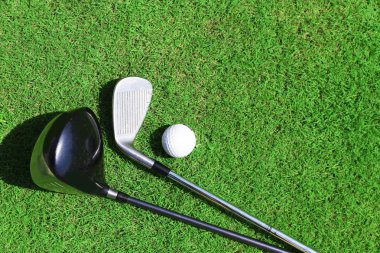 Golf kulüpleri ve top yeşil çimenlerin üzerinde