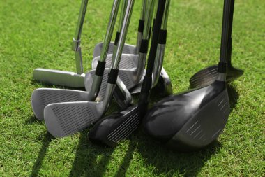 Yeşil lüks golf sahası üzerinde farklı pahalı golf kulüpleri