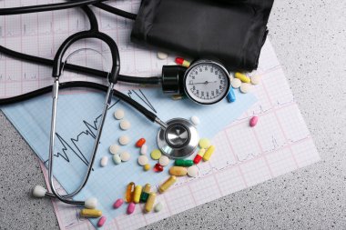 Tansiyon ölçer, hap ve gri arka plan üzerinde stetoskop