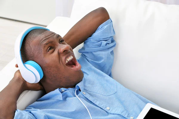 Handsome African American man with headphones lying on sofa close up — Stock Photo, Image