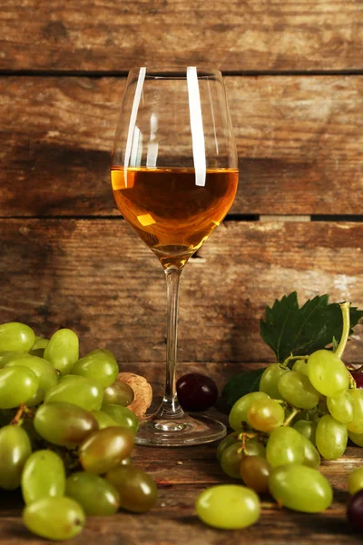 Виноград с бокалом вина на фоне дерева — стоковое фото