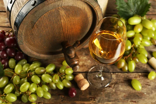 Uva blanca y roja con botella de vino cerca del barril sobre fondo de madera — Foto de Stock