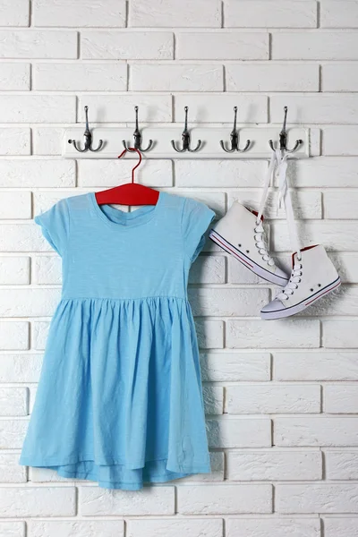 Детское платье на вешалке на фоне белой стены — стоковое фото