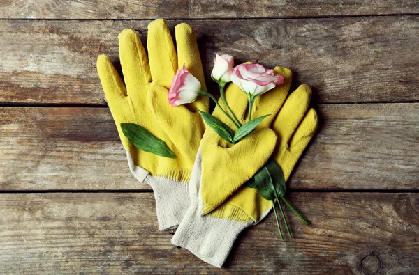 Composizione di guanti gialli di fiori e giardinieri sensibili su fondo di legno — Foto Stock