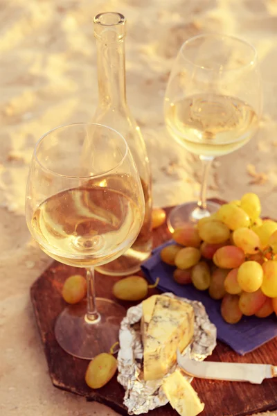 Composizione romantica di vino bianco e uva sulla spiaggia sabbiosa — Foto Stock