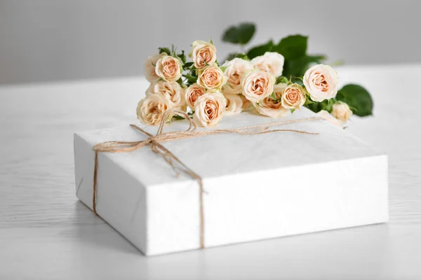 Big white gift box with bouquet of roses on the table — Stock Photo, Image