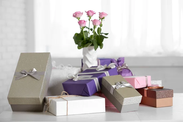 Composition de mignons coffrets cadeaux et roses sur table blanche — Photo