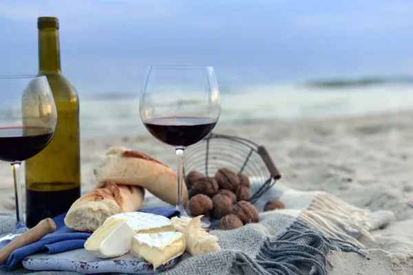 Hermosa composición romántica de vino tinto, pan y nueces en la playa de arena — Foto de Stock