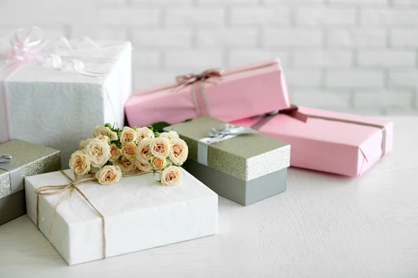 Coffrets cadeaux décorés et bouquet de roses sur fond mural en brique blanche — Photo