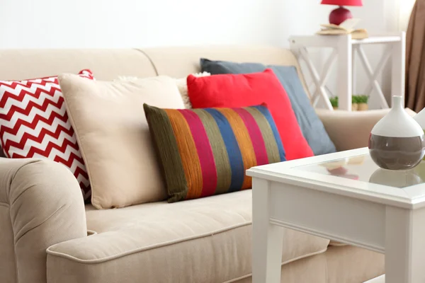 Kényelmes kanapéval és színes párnák, homályos szobabelső — Stock Fotó