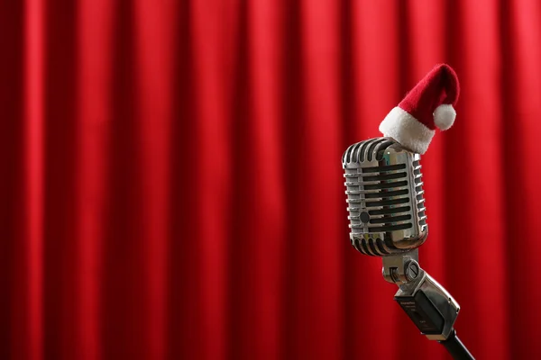 Micrófono vintage con pequeño sombrero de Navidad sobre fondo de cortina roja —  Fotos de Stock
