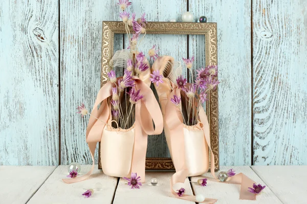 Decorated with flowers and candles ballet shoes in frame on blue wooden background — Stock Photo, Image