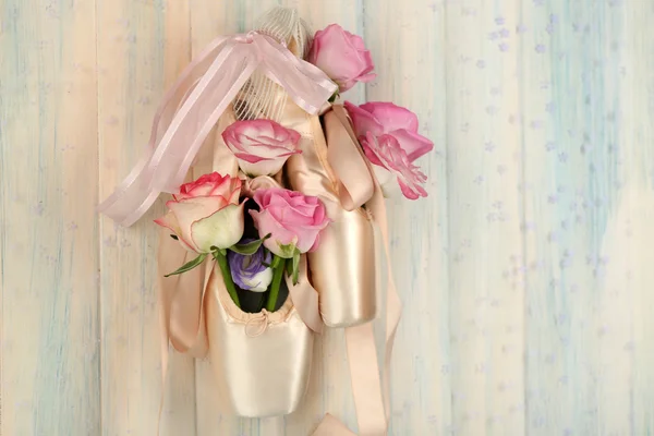 Прикрашені балетні туфлі з трояндами в ній висять на світлому дерев'яному тлі — стокове фото