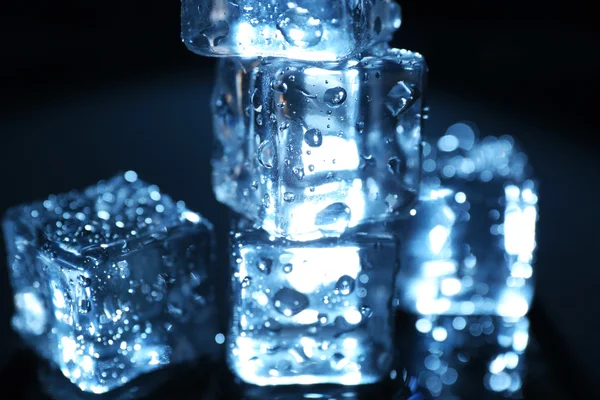 Cubos de hielo brillantes bajo luz azul sobre fondo líquido —  Fotos de Stock